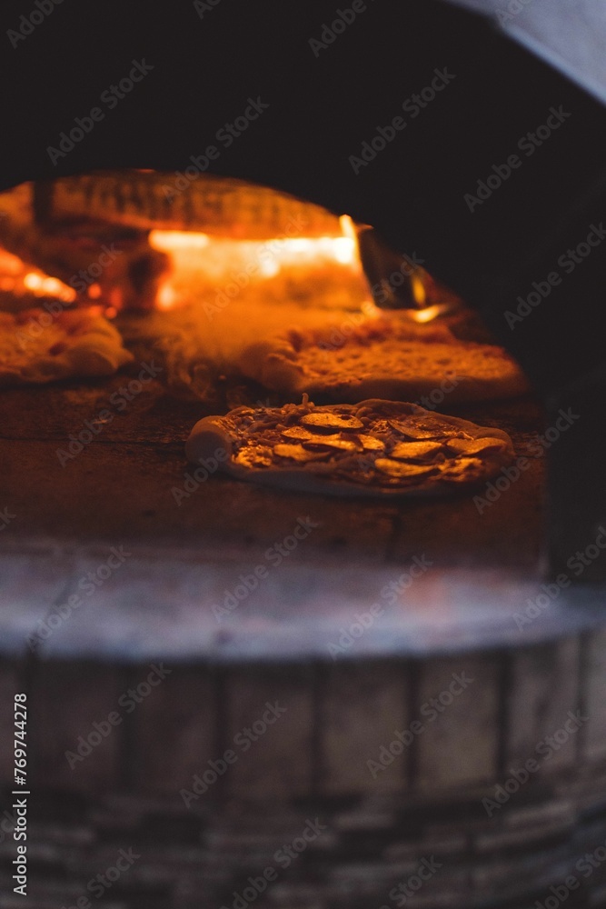 a pizza sitting inside of a brick oven, in a pizza kitchen