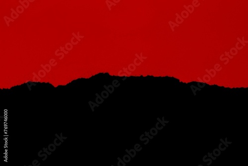 Red, torn cardboard piece isolated on a black background, illuminated by natural light © Wirestock