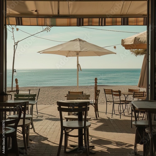 A seaside cafe with empty chairs and tables, facing a quiet beach and a calm sea