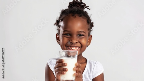 World Milk Day, 5 year old African girl sits smiling holding a glass of healthy milk.