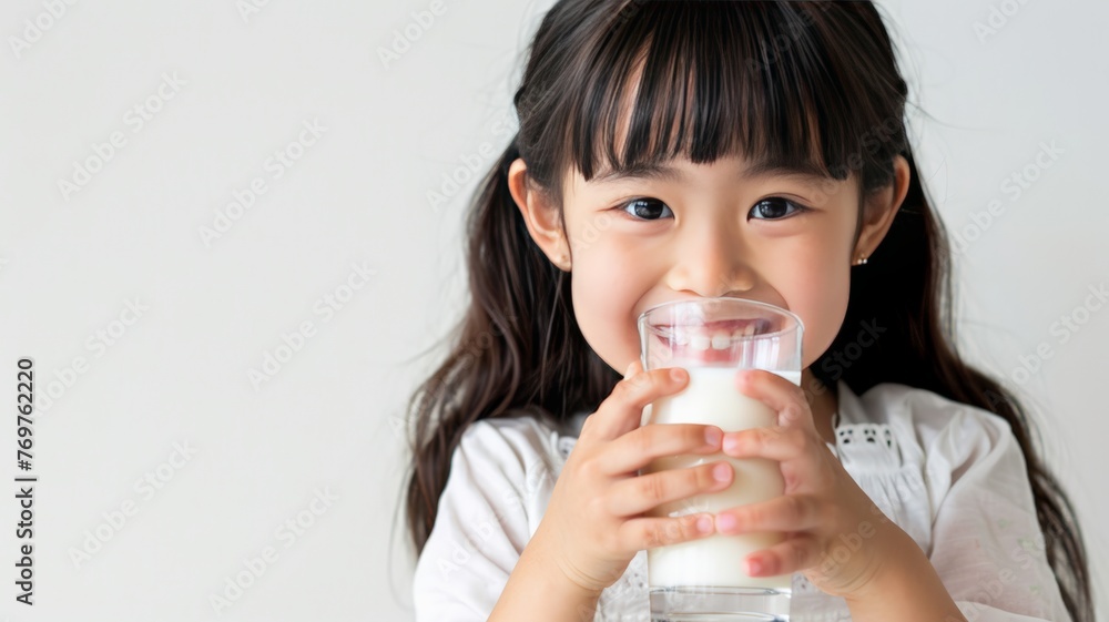 World Milk Day, Five year old Asian girl sits holding a glass of healthy milk. World Milk Day, Five year old Asian girl sits holding a glass of healthy milk.