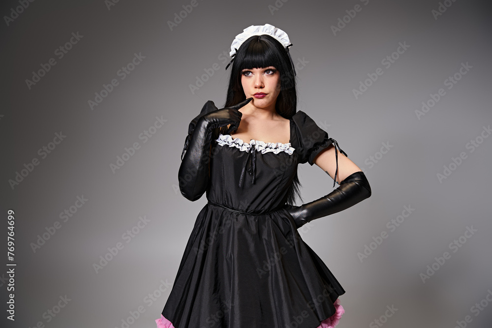 appealing young cosplayer in maid costume posing alluringly and looking away on gray backdrop appealing young cosplayer in maid costume posing alluringly and looking away on gray backdrop