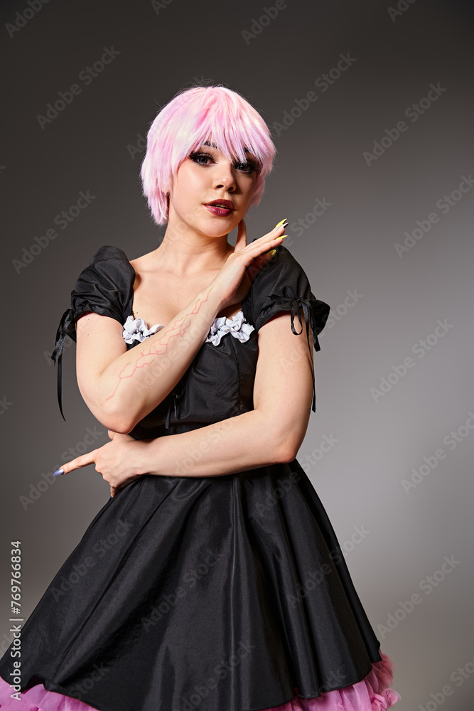 pretty appealing cosplayer in sexy maid costume with pink hair looking at camera on gray backdrop pretty appealing cosplayer in sexy maid costume with pink hair looking at camera on gray backdrop
