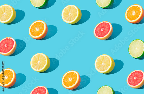 Colorful sunlight fruit pattern made of red grapefruit, orange, lime and lemon slices on light blue background with copy space. Minimal summer concept. Creative food idea. Citrus fruits aesthetic. © Jakov