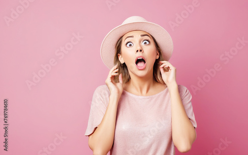 Portrait of a woman with hat and surprised look on pink background photo