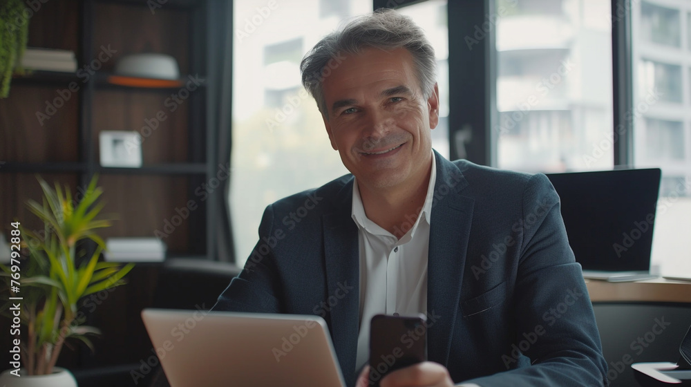 Middle aged Caucasian business manager ceo using smartphone and laptop in office working with copy space Middle aged Caucasian business manager ceo using smartphone and laptop in office working with copy space