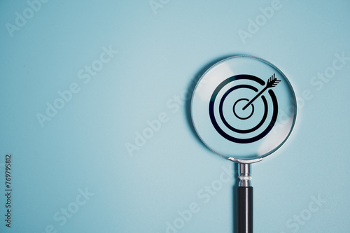 Target board inside vintage magnifying glass  for focus business objective on blue background and copy space.