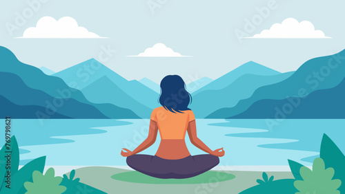  A woman sits at the edge of a serene lake her legs crossed and her palms facing upwards in a mudra of peace. She gazes out at the calm water © Justlight