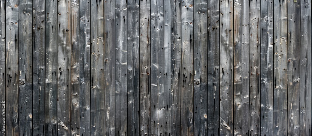 Fototapeta premium Vertical wooden fence made from rough grey planks with cracks, nails, and scratches. Old horizontal wood texture.