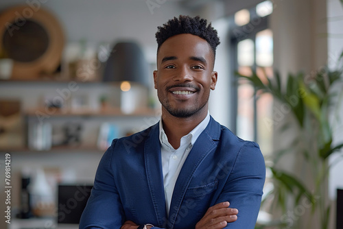 Portrait of a Confident Young African American Businessman Standing in Office in a Blue Business Suit. Successful Corporate Manager Posing for Camera with Crossed Arms, Smiling Cheerfully photo