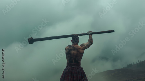 A muscular man in a kilt holds a massive caber against a misty backdrop, a moment before the traditional toss