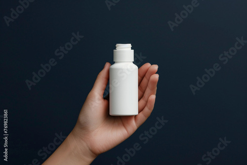Hand showcasing an empty white skincare product bottle against a matte navy isolated solid background, symbolizing reliability and depth in skincare,