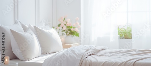 White linens cover a comfortable bed made of wood with matching pillows in a bedroom with hardwood flooring. A plant adds a touch of nature near the window
