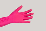 Closeup of woman hand wearing pink rubber glove showing her open palm give me something. Indoor studio shot isolated on gray background.