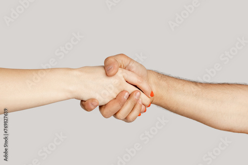 Closeup of diverse woman and man handshaking, agreement sign, greeting eachother. showing Indoor studio shot isolated on gray background.