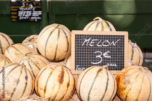 Front view, close distance of, a pile of cantaloupe melons with a pricing sign