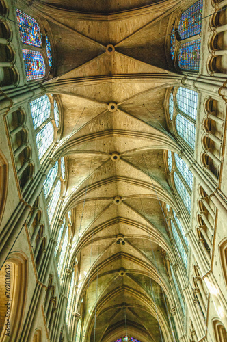 Bottom view, medium distance of, rows of vaulted, arched ceilings with two rows of stained glass windows in Remy, France