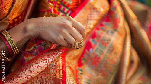 Indian bride's hand adorned with henna tattoo and traditional bangles selecting a vibrant saree wedding attire