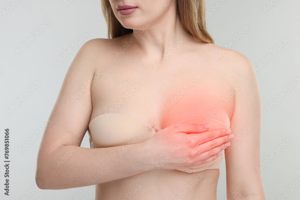 Young woman suffering from breast pain on light grey background, closeup Young woman suffering from breast pain on light grey background, closeup