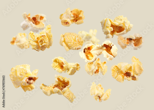 Tasty fresh popcorn flying on light grey background