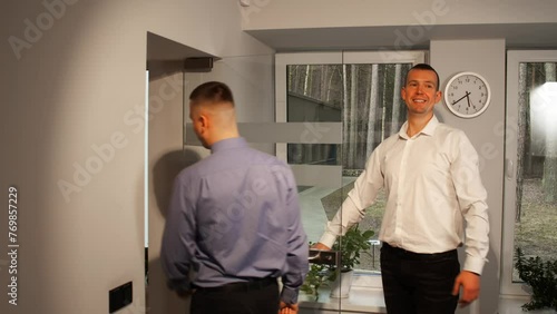 Businessman inviting colleagues to office with hand gesture and opening glass doors to gathered in office to discuss and strategize business solutions office work concept. Business Attire 