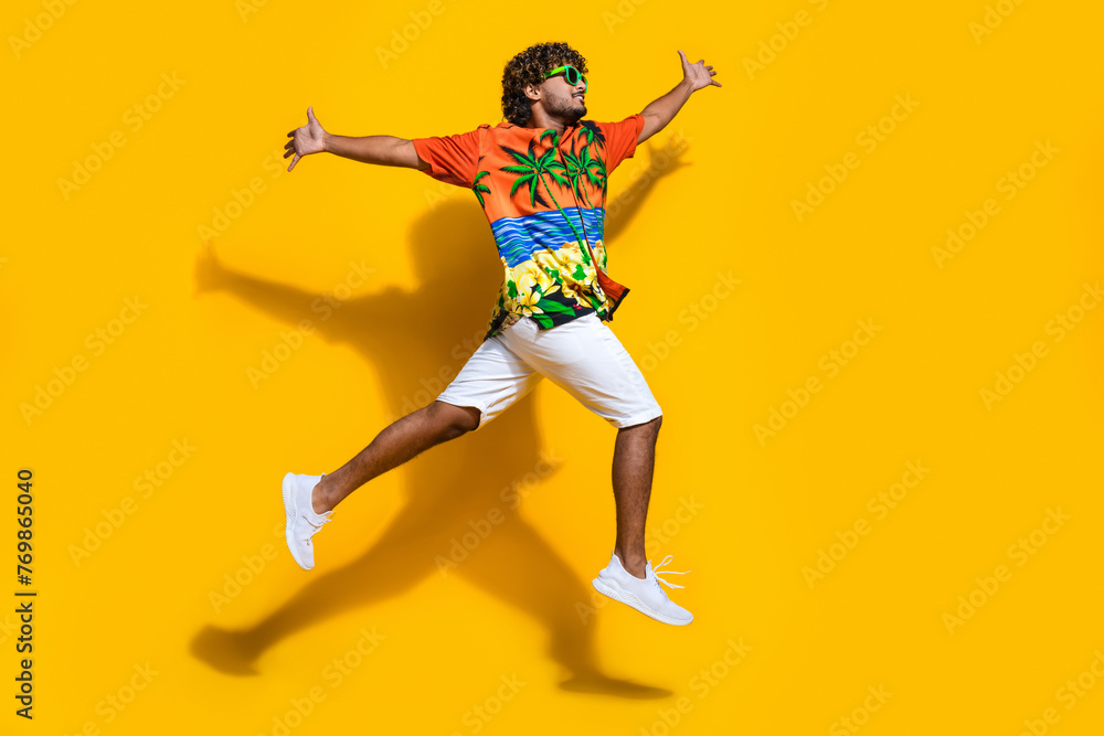 Full size photo of good mood man dressed print shirt flying open palms look at logo empty space isolated on yellow color background Full size photo of good mood man dressed print shirt flying open palms look at logo empty space isolated on yellow color background
