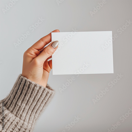 a woman hand holding a blank white postcard ,against a minimal background 