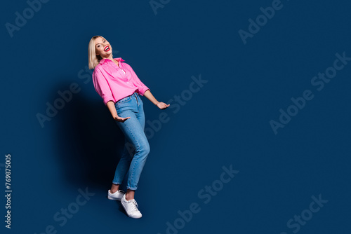 Full size photo of positive girl dressed pink shirt jeans arms hold big invisible box empty space isolated on dark blue color background © deagreez