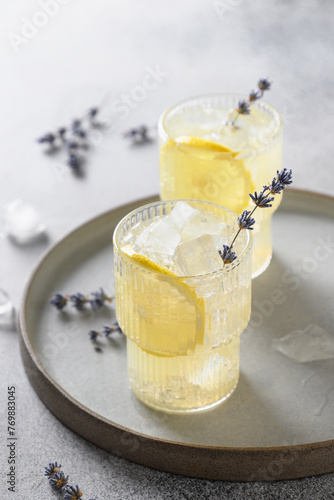 Sparkling lavender lemonade in glasses on gray background. Vertical format. Close up. Summer aroma freshness soft drink.