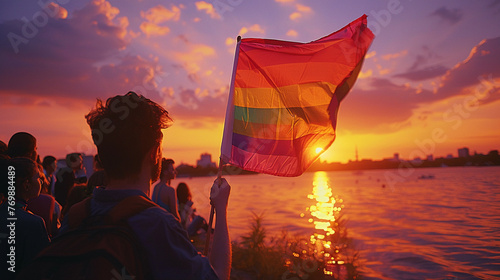 A group of young individuals at a lakeside gay pride celebration the rainbow flag catching the breeze photo