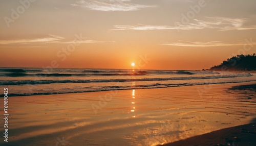  The sun sets over the ocean as waves roll in and out of the water on the beach