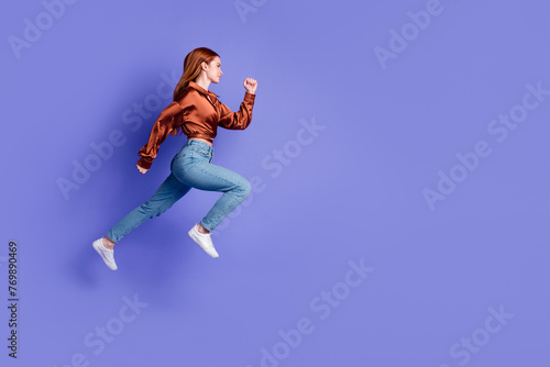 Full length profile portrait of nice young woman jump run empty space wear brown shirt isolated on purple color background