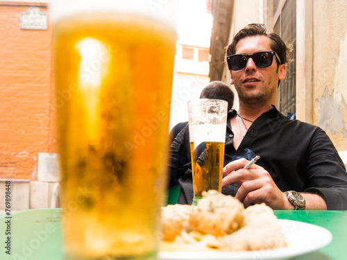 man in his thirties with sunglasses beer and cigar on the terrace of the bar