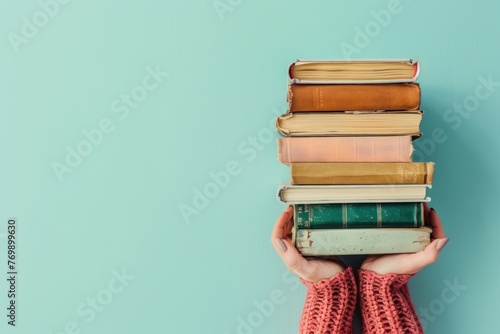 Woman hands holding pile of books over light blue background photo