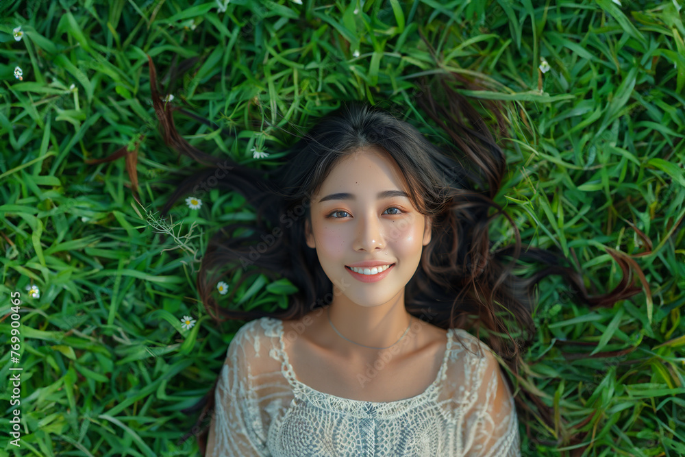 Beautiful young Asian Chinese woman with very long volume shine natural healthy hair smiling lying on grass field on nature background top view hair products concept Beautiful young Asian Chinese woman with very long volume shine natural healthy hair smiling lying on grass field on nature background top view hair products concept