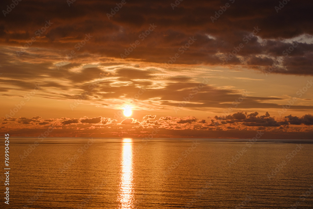 Fototapeta premium Romantic colorful sunset at the sea. View of Beautiful glorious golden sunset and golden hour above the sea in evening.