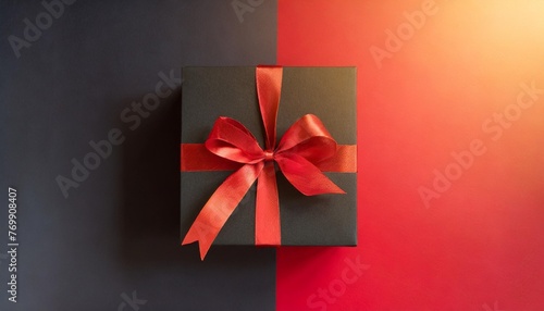 top view of black giftbox with red ribbon on two color red and black background with copy space