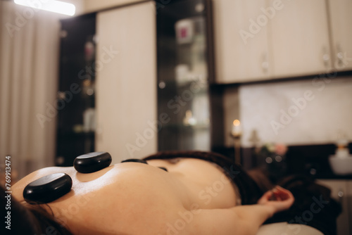 Woman getting spa treatment. Hot stone therapy. brown color
