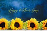 Row of beautiful sunflowers for Mother's Day against a blue painterly background with writing text. Front view. Selective focus with blurred background.