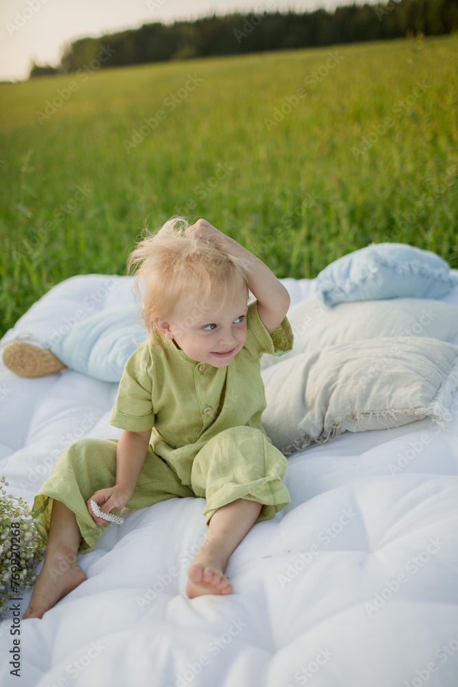 little girl child sitting on the grass and playing with hat and pillows little girl child sitting on the grass and playing with hat and pillows