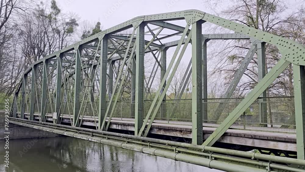 A truss bridge made of steel crosses the Leine river, with trees in the background Maschsee Hanover