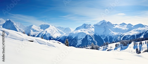 A picturesque natural landscape featuring a snowy mountain range under a clear blue sky, creating a stunning contrast between the white snowcapped peaks and the vibrant blue hues of the sky