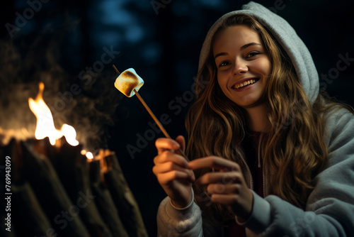 Young girl roasting a marshmallow on a stick on camping trip
