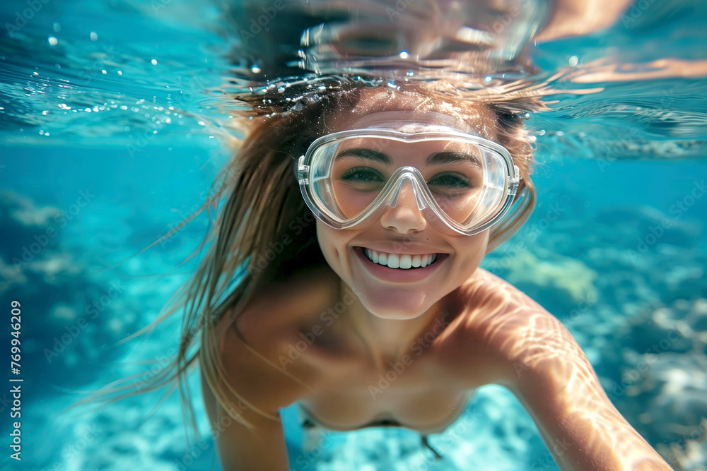 Naklejka premium Underwater Portrait of a Joyful Woman Snorkeling in Clear Tropical Waters and smiling at camera