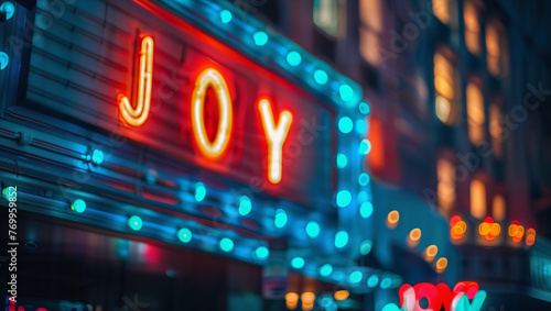 The word "JOY" in the form of an old cinema marquee in a city with blurred streetlights in the background.