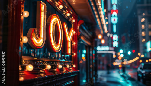 The word "JOY" in the form of an old cinema marquee in a city with blurred streetlights in the background.