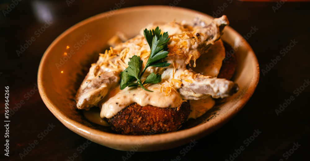 A succulent rabbit shoulder blade garnished with herbs and creamy sauce