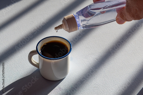 Canvas Print person sweetening coffee with liquid sweetener