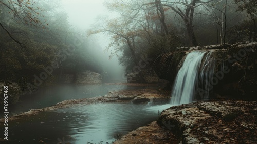 Waterfall in a serene misty forest - A tranquil waterfall flows gently into a calm pool nestled within an atmospheric misty forest