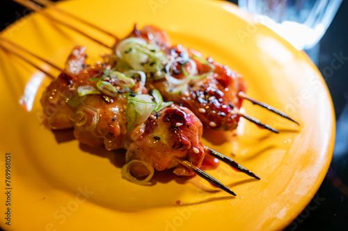 Wooden skewers with pieces of chicken fillet in teriyaki sauce from the grill served at yakitori restaurant in Milan, Italy. photo